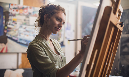 student draws on a canvas in an art studio setting