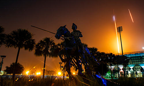 UCF Knight on a horse in front of a rocket launch over the UCF football stadium at night