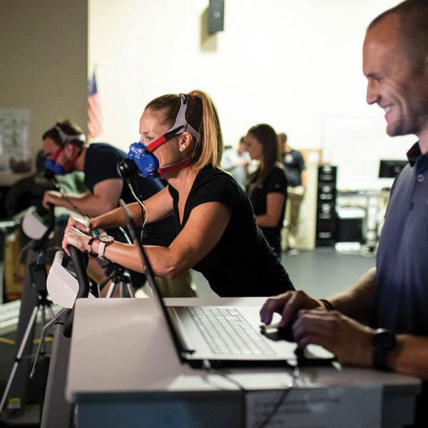 Researcher standing next to subjects working on treadmills during a test