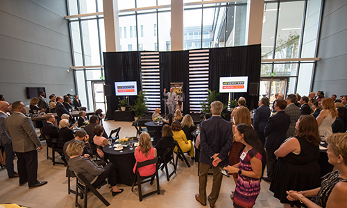 Donors sitting at a tabled event with a speaker on stage