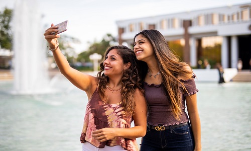 two students pose for a selfie in front of Millican Hall